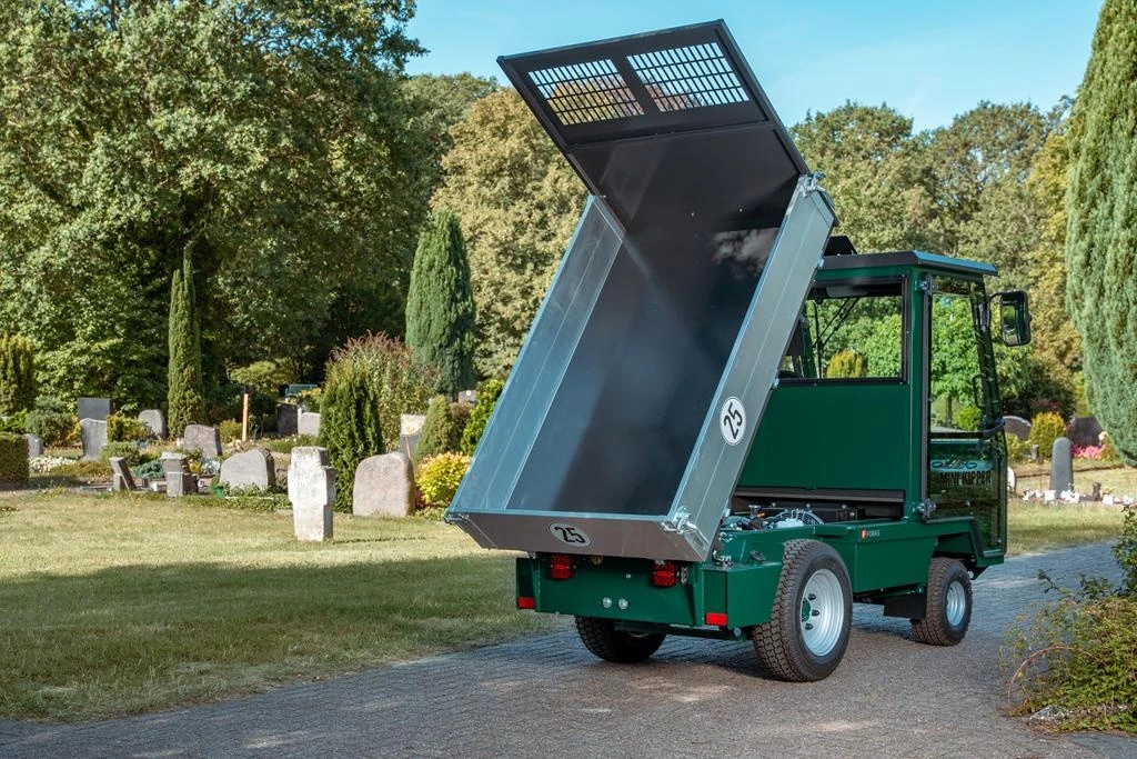 Grüner Mini-Kipper von hinten mit hochgekippter verzinkter Mulde auf einem Friedhof